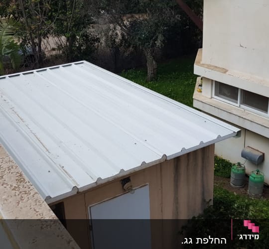 גג מתכת לבן על מבנה קטן בחצר